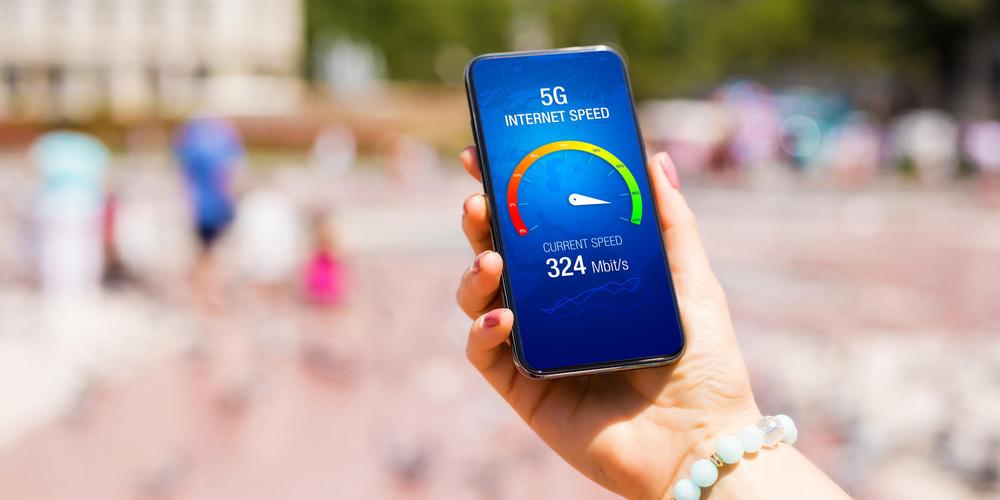 Eine Hand hält ein Smartphone auf dessen Display man einen 5G-Speedtest sieht